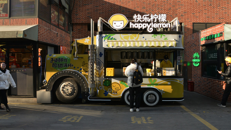 A person standing in front of a Happy Lemon Boba truck