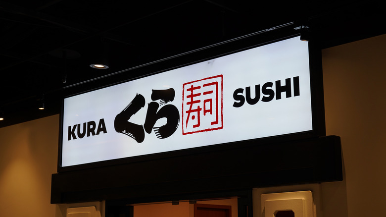 A white, black, and red Kura Sushi sign