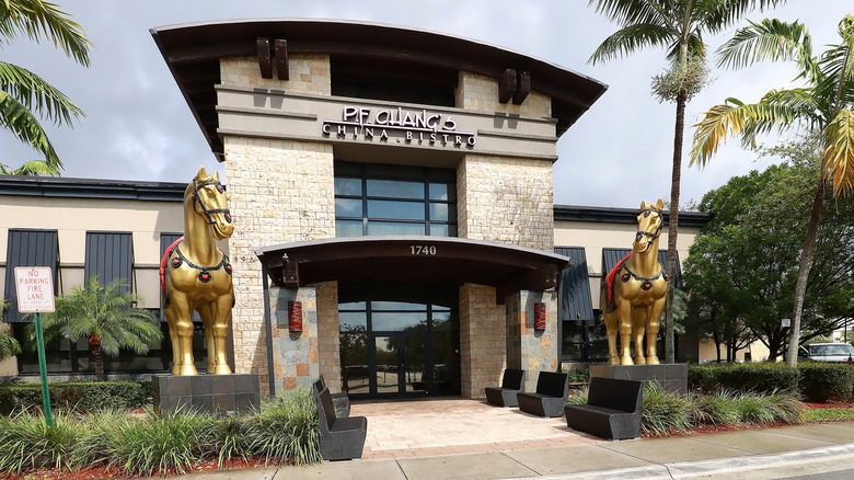 The outside of a P.F. Chang's restaurant with two giant gold horse statues.