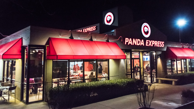 The outside of a lit up Panda Express restaurant at night