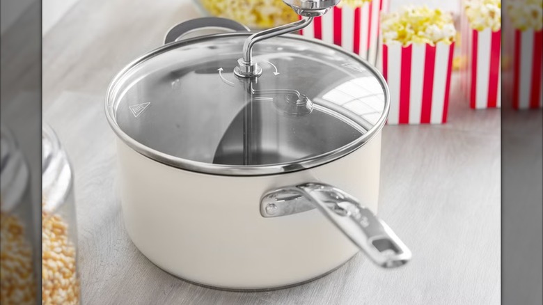 Stainless steel popcorn maker on table.