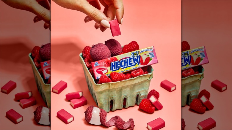 Package of Hi-Chew in a basket with raspberries and lychees.