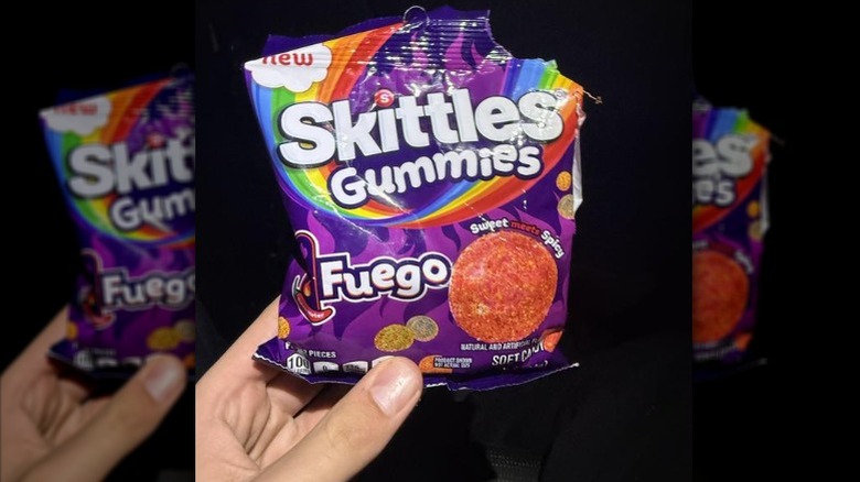 Person holding a bag of Skittles Gummies Fuego candy.