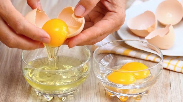 Hands cracking eggs into a small dish