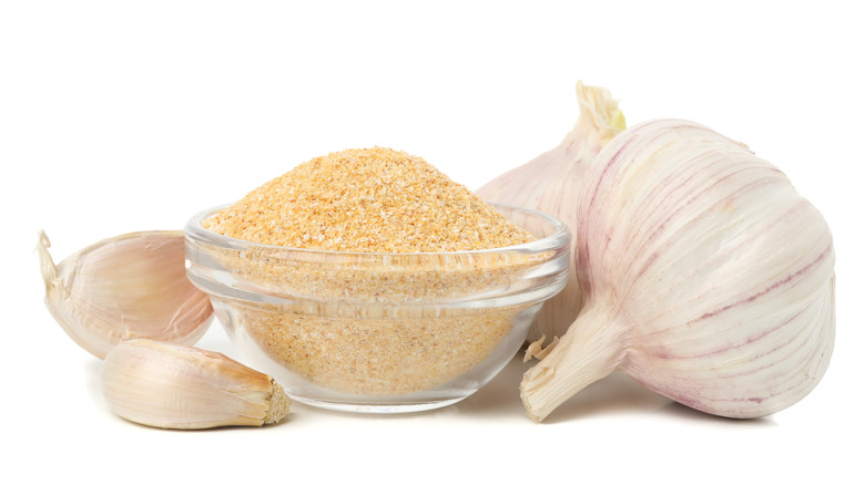 Bowl of garlic powder with garlic bulbs