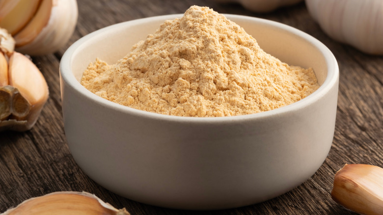 Bowl of garlic powder with garlic bulbs