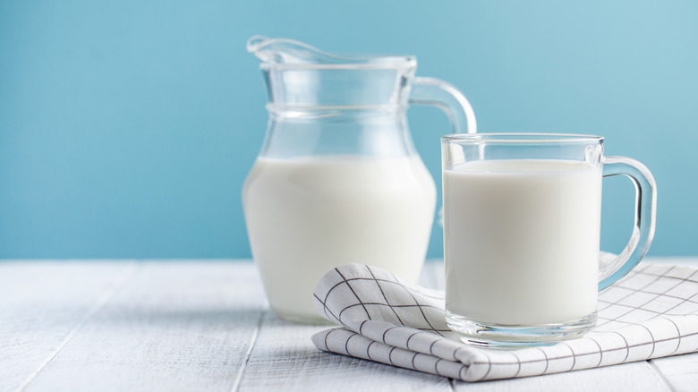 Jar and glass of cream with blue background