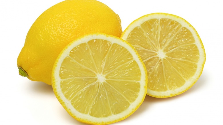 A whole lemon, half lemon, and lemon wedge on white background