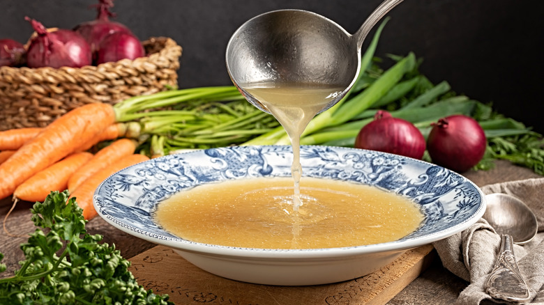 A ladle pouring vegetable broth in a bowl