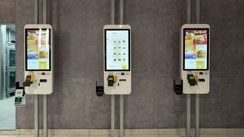 Three self-ordering machines in a McDonald's restaurant.