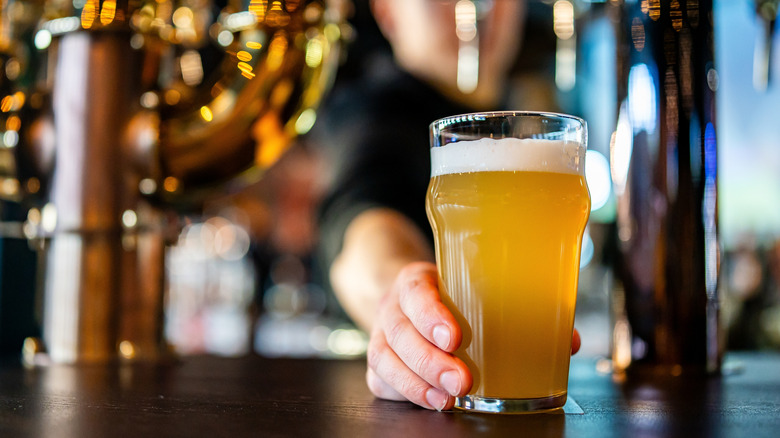 Bartender's hand sliding beer across bar