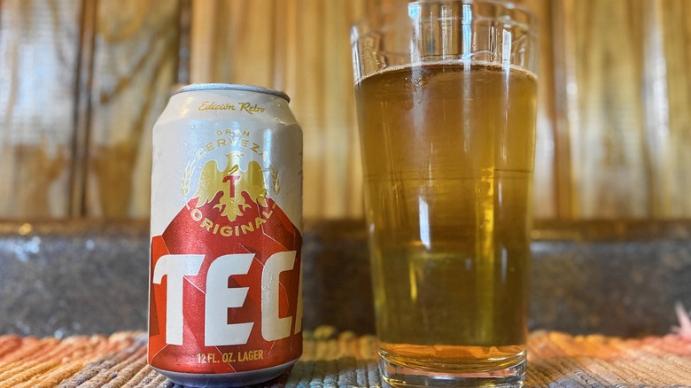 Tecate can next to glass of beer