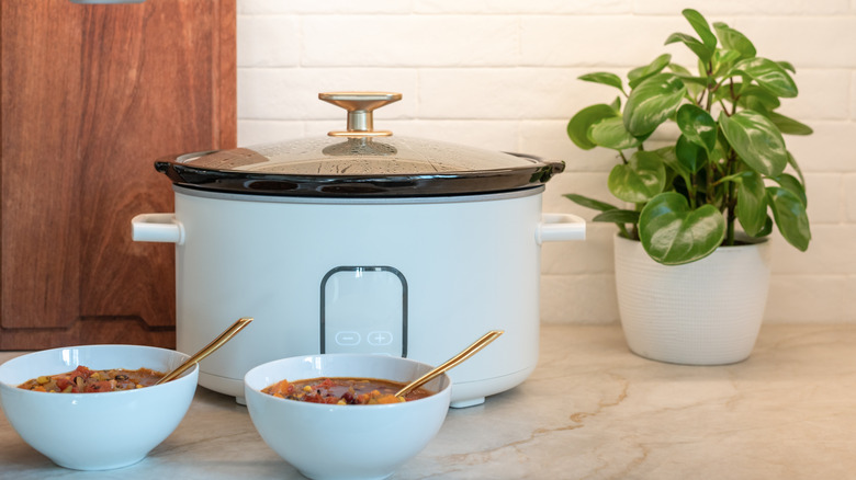 White crockpot with two bowls of soup sitting on a counter