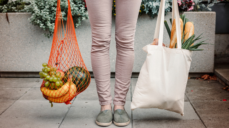 Person holding groceries in reusable bags