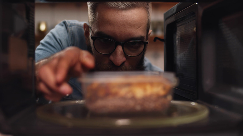 Man with leftover food in microwave