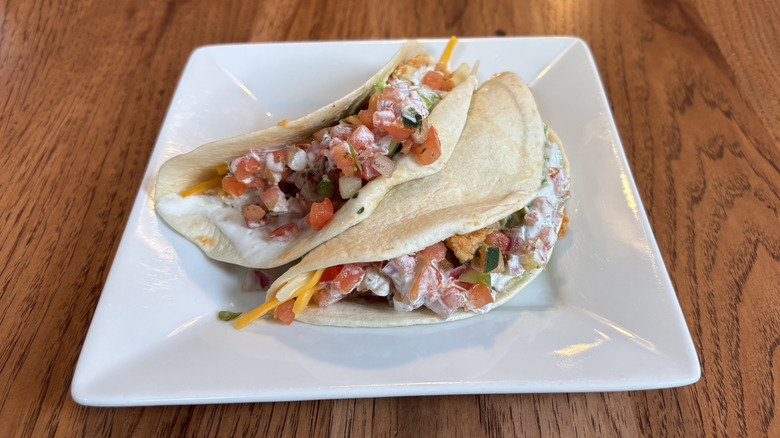 two chicken tacos with pico de gallo on a plate