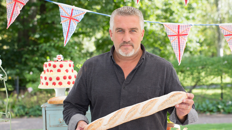The Great British Bake Off judge Paul Hollywood holding a baguette while on set