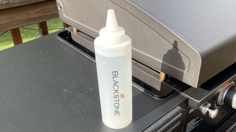 One water-filled squeeze bottle sitting on a Blackstone griddle