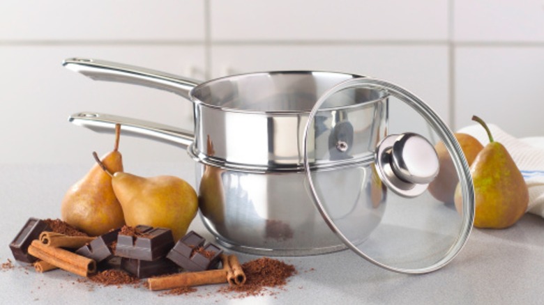 double boiler on white kitchen counter surrounded by pears and chocolate