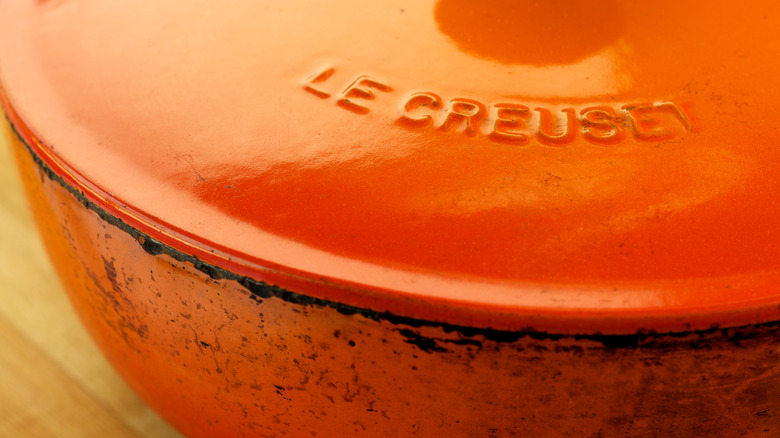 Close up of orange lid and label on well-worn Le Creuset pot