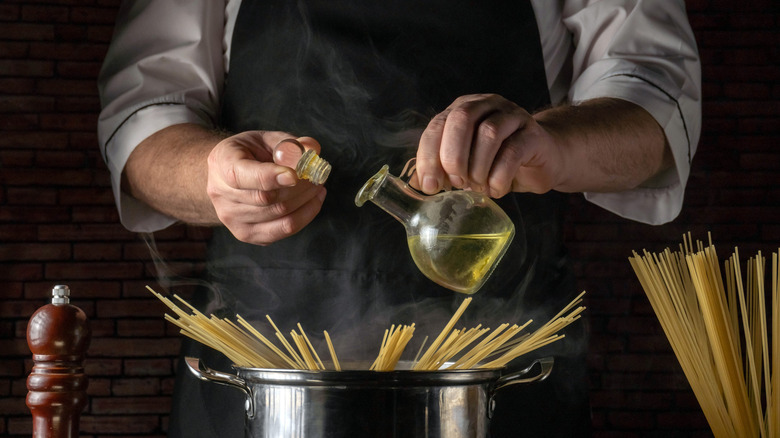 Chef pouring oil into pasta water