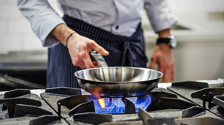 Chef heating pan on stove