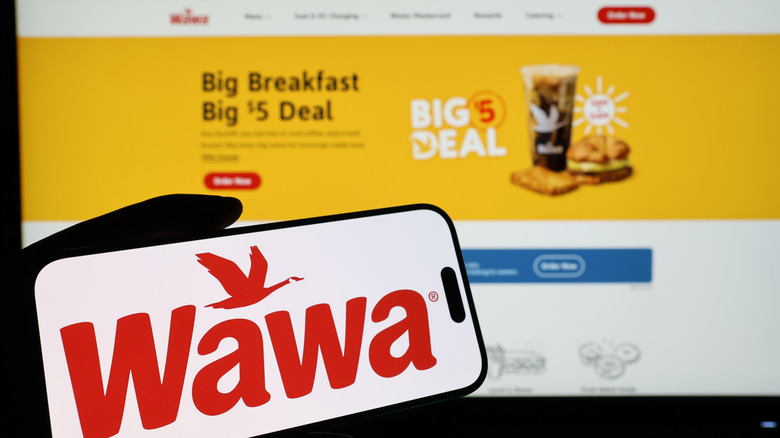 Wawa logo on a smartphone with website behind it