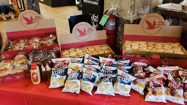 A table full of Wawa catering hoagies, pretzels, cookies, and chips
