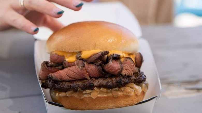 Hand reaching for a prime rib burger
