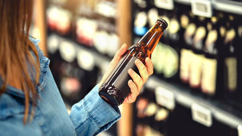 woman's hand holding a blank beer bottle