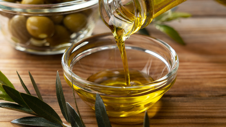 olive oil being poured into glass bowl