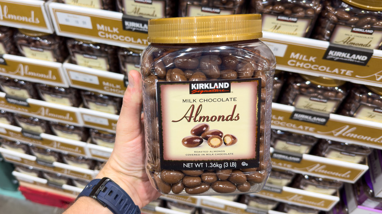 A hand holding Kirkland Signature chocolate-covered almonds