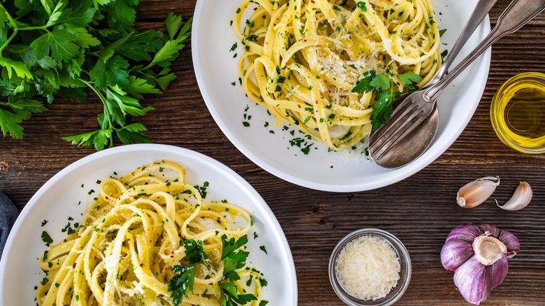 Two bowls of spaghetti aglio e olio with fresh parsley