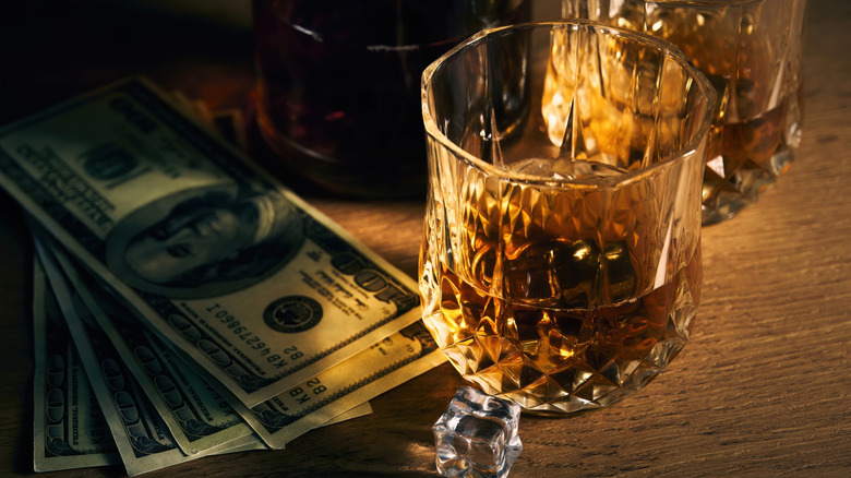 Glass of bourbon and stack of hundred dollar bills