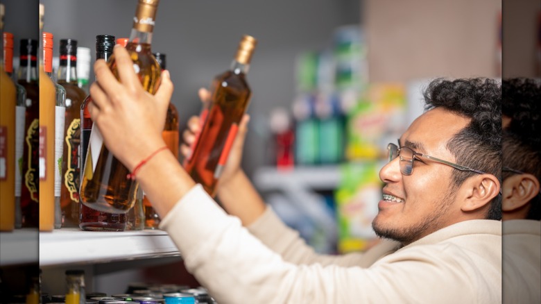 Customer grabs two bottles of liquor from top shelf in store