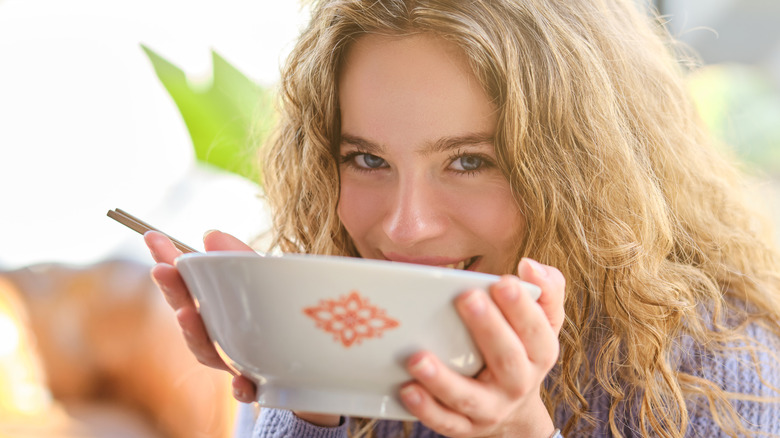 Girl smiling into a bowl of soup