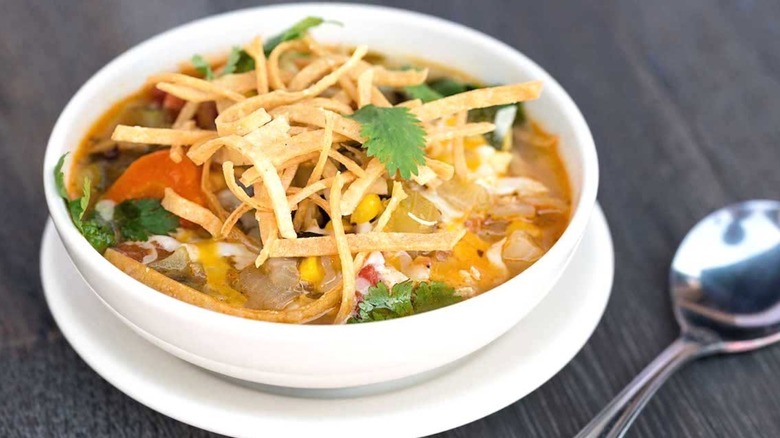 Close-up of The Cheesecake Factory's Chicken Tortilla Soup in a white bowl with a spoon on the side