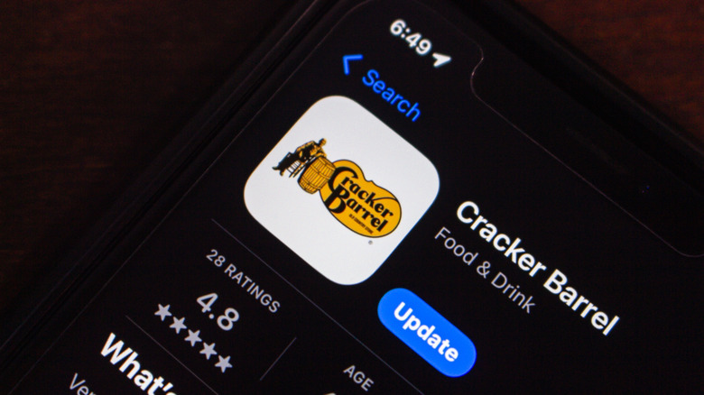 close-up of a phone lying on a dark table, open to app store, displaying the Cracker Barrel app