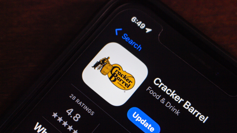 close-up of a phone lying on a dark table, open to app store, displaying the Cracker Barrel app
