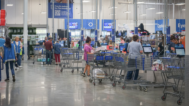 Shoppers in Sam's Club at the checkout lanes with their carts.