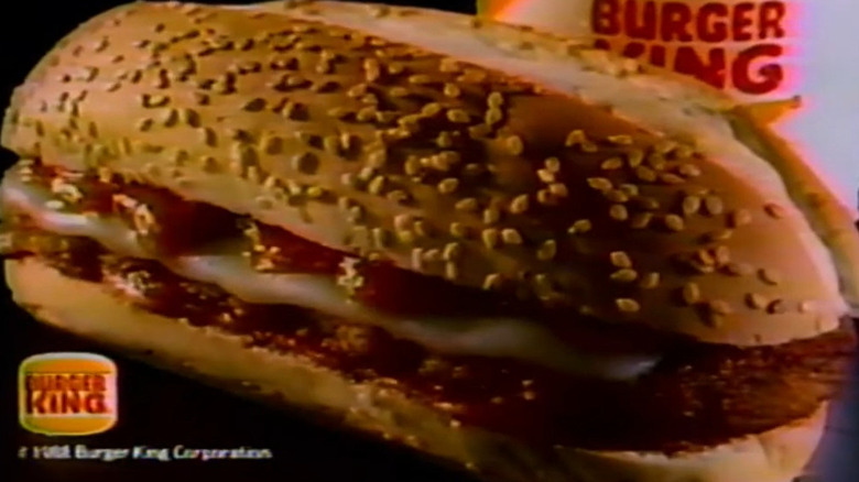 Burger King's Veal Parmigiana Sandwich rests against a Burger King soda cup.