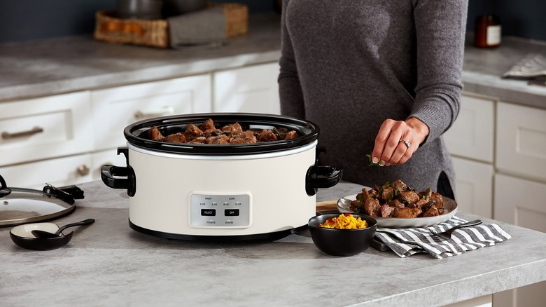 Had of woman adding herbs and texture to a slow cooker meal