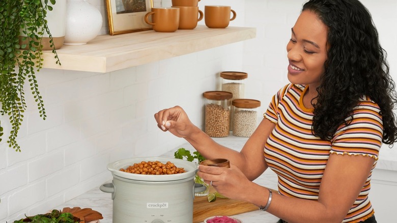 Woman adding seasoning to a crockpot meal