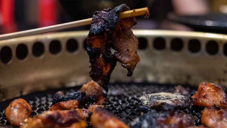 Overcooked food with black tar substance. Eating unhealthy burnt food is dangerous & can cause cancer. Carcinogenic comes from barbecue which is prone to cause cancer. Unhealthy lifestyle concept.