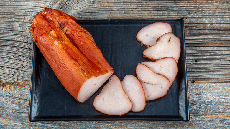 Smoked turkey meat. Roasted sliced Christmas ham of turkey on dark rustic background. Festival food.
