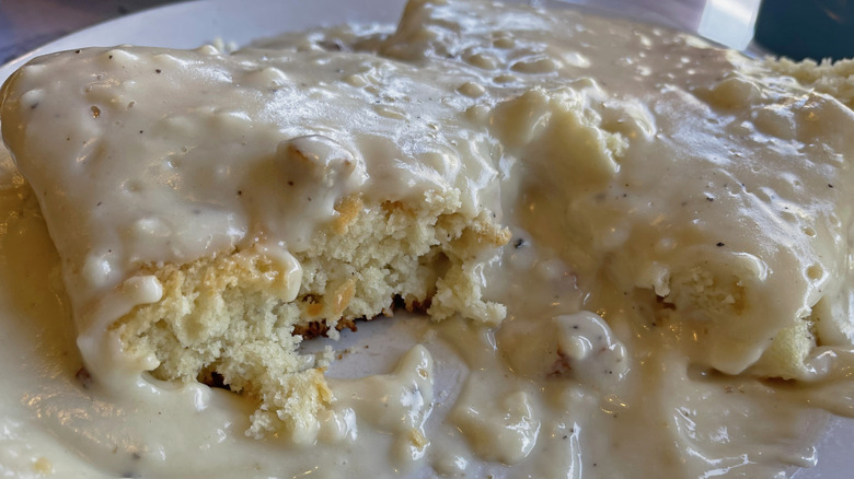 Biscuits drowning in gravy, one with a bite taken out of it