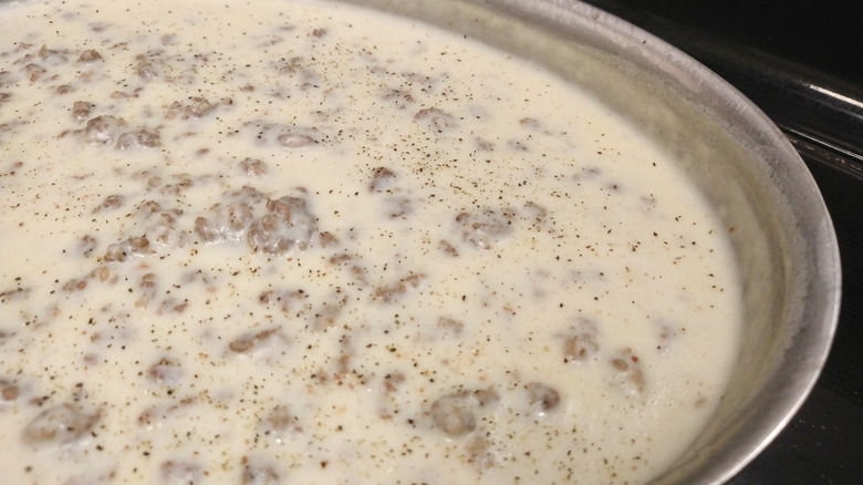 White sausage gravy in a pan with black pepper