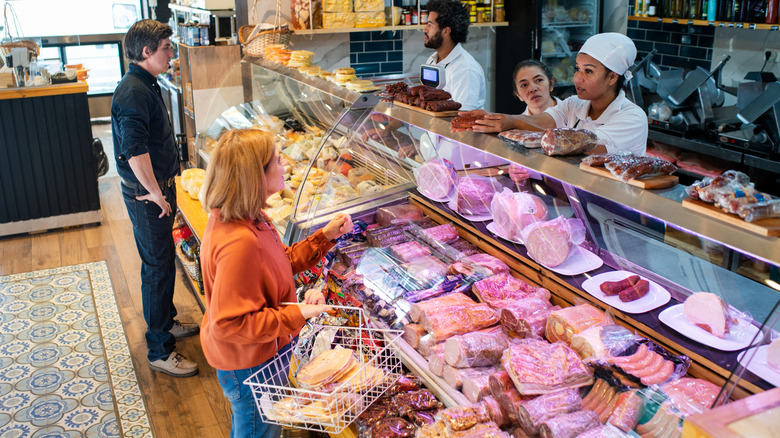 Customers picking out sausage at a market's meat counter