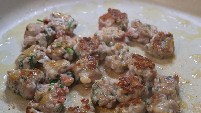 A close-up of crumbled sausage browning in a pan