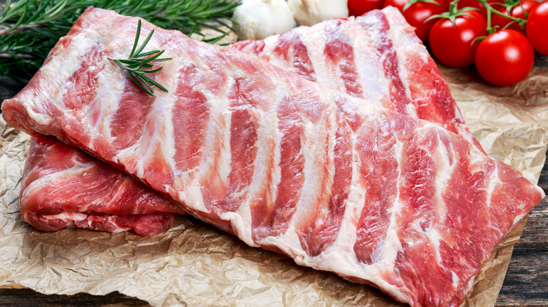 Raw ribs on butcher paper with a sprig of rosemary